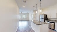Located at 2130 Mayport Rd in Jacksonville, FL, this single-story, 3-bedroom, 2-bathroom home offers a well-designed open-concept layout that seamlessly connects the kitchen, dining, and living areas. The kitchen is a standout feature, showcasing white shaker cabinetry, granite countertops, stainless steel appliances including a refrigerator and range, a subway tile backsplash, and a central island with pendant lighting overhead. Hardwood-style flooring runs throughout the main living areas, adding warmth and continuity to the space. The living room is bright and airy, benefiting from multiple windows and a ceiling fan. The three bedrooms are carpeted for comfort, with the primary bedroom offering a generous footprint, a ceiling fan, and access to a private bathroom featuring granite countertops and white cabinetry. A walk-in closet with built-in wire shelving systems provides ample storage. The secondary bedrooms are well-sized with natural light from windows. A dedicated laundry room and additional closets enhance functionality. A covered patio extends the living space outdoors, offering views of the surrounding community. This home combines modern finishes with practical design throughout.