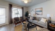 This single-floor residence offers a thoughtfully designed layout that balances functionality with contemporary style throughout its interconnected living spaces. The kitchen is a standout feature, showcasing rich dark-stained cabinetry extending to the ceiling, stainless steel appliances including a refrigerator, range, and microwave, and clean white countertops. A peninsula with bar seating provides a casual dining option, while light wood-style flooring ties the space to the adjacent areas seamlessly.

The separate dining area accommodates a round table beneath track lighting, creating an intimate setting with clean sightlines to the rest of the unit. The living room is bright and welcoming, with large windows fitted with drapes that allow generous natural light and views of the surrounding exterior. Soft, neutral wall tones provide a versatile backdrop throughout.

The bedrooms are carpeted for comfort, each offering multiple windows, ample natural light, and closet storage. The full bathroom features dark cabinetry consistent with the kitchen, a white countertop vanity with a wide mirror, and a tub-shower combination. A dedicated in-unit laundry area with a stacked washer and dryer adds practical convenience to this well-rounded residence.