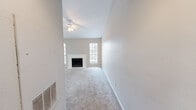 This well-organized single-story residence offers a thoughtful layout across one bedroom, one bathroom, and a collection of functional living spaces. The living room serves as the heart of the home, highlighted by a classic white-surround fireplace flanked by windows that invite natural light. Soft carpeting, neutral warm-toned walls, and a ceiling fan complete the comfortable, airy atmosphere. An open passthrough connects the living area to the kitchen, which features dark espresso cabinetry, white countertops, a stainless steel sink, and black appliances including a range and refrigerator. Light wood-tone flooring grounds the kitchen's galley-style layout. A breakfast bar overlooking the living room adds convenient dining or prep space. The bedroom is a generously sized, carpeted retreat with its own ceiling fan and access to a walk-in closet equipped with wire shelving for organized storage. A second closet provides additional flexibility. The bathroom is clean and bright, offering a full tub-shower combination with white tile surround and tile flooring. A hallway connects the rooms efficiently, completing this practical and move-in ready floor plan.