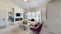 This thoughtfully designed single-story residence offers 1 bedroom and 2 bathrooms across a compact yet efficiently organized floor plan. The open-concept living, dining, and kitchen area creates a seamless flow ideal for both everyday living and entertaining. The living room is highlighted by a sleek wall-mounted electric fireplace, a wall-mounted television, and large windows that invite abundant natural light and outdoor views. A dedicated dining area accommodates a full-sized table and benefits from its own exterior-facing window. The kitchen is well-equipped with rich dark cabinetry, marble-style countertops, a subway tile backsplash, stainless steel appliances, and a breakfast bar with seating for two. The spacious primary bedroom features a ceiling fan, multiple windows for natural light, and generous space for a sitting area. Both bathrooms are finished with dark vanity cabinetry and marble-style countertops, with one bathroom accessible from the main living area. A dedicated laundry area with washer/dryer hookups and an electrical panel is conveniently located within the unit. Neutral tones, carpet flooring in living and sleeping areas, and wood-style tile in wet areas contribute to a cohesive and contemporary aesthetic throughout.