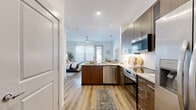 Located at 12500 Live Oak Way in Frisco, Texas, this thoughtfully designed studio unit offers a single-floor open-concept layout that seamlessly integrates the living, dining, and sleeping areas into one cohesive space. Light wood-tone flooring runs throughout, lending warmth and visual continuity from room to room.

The kitchen is a standout feature, outfitted with rich dark walnut-toned cabinetry, granite-look countertops, a white subway tile backsplash, and a full suite of stainless steel appliances including a refrigerator with ice maker, electric range, built-in microwave, and dishwasher. A peninsula provides additional counter space and serves as a natural divide between the kitchen and the living area.

The open living and sleeping zone benefits from a ceiling fan, recessed lighting, and a sliding glass door that invites natural light and provides access to a private outdoor area with exterior views. The clean white walls and bright atmosphere contribute to an airy, open feel throughout.

The bathroom is finished with large-format neutral tile, a soaking tub with shower, a granite-topped vanity with dark wood cabinetry, and overhead storage. Additional conveniences include a dedicated closet and an in-unit laundry area, ensuring practical functionality within the compact yet well-appointed floor plan.