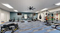 Imagine stepping into your very own wellness oasis, where every fitness dream becomes a reality. This expansive 940 square foot space is not just a gym; it's a lifestyle upgrade that will revolutionize your approach to health and well-being. The moment you enter, you're greeted by a sleek, modern design that seamlessly blends functionality with inspiration.

The main fitness area boasts an impressive array of top-of-the-line equipment, including treadmills, ellipticals, and strength training machines, all arranged to maximize your workout efficiency. The vibrant blue and gray flooring adds a touch of energy and motivation to your exercise routine. Overhead, a modern ceiling fan ensures optimal air circulation, keeping you cool and comfortable during even the most intense sessions.

But this space offers more than just physical fitness. Adjacent to the main area, you'll find a dedicated zone for mindfulness and relaxation. The colorful, playful flooring in this section creates a cheerful atmosphere perfect for yoga, meditation, or simply unwinding after a rigorous workout. A cozy seating area with contemporary furniture provides the ideal spot for post-workout recovery or small group fitness classes.

Large windows and French doors flood the space with natural light, creating an uplifting environment that will inspire you to push your limits and achieve your goals. Whether you're an early riser or a night owl, this 24/7 accessible fitness center adapts to your schedule, making it easier than ever to prioritize your health and wellness.

Transform your life and unlock your full potential with this extraordinary fitness space – your personal key to a healthier, happier you.