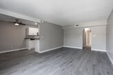 Located at 2900 E Tahquitz Canyon Way in the heart of Palm Springs, California, this single-floor unit offers a clean, contemporary living environment with thoughtful updates throughout. The open living and dining area is finished with light gray wood-look flooring that runs consistently through the space, creating a cohesive and modern feel. A ceiling fan provides comfort in the main living area, which connects seamlessly to the kitchen and benefits from natural light streaming in through large sliding glass doors that open to an outdoor space with views of palm trees and neighboring greenery.

The galley-style kitchen is well-appointed with white cabinetry, dark granite-style countertops, a double-basin sink, and black appliances including a gas range, microwave, and refrigerator. Ample upper and lower cabinet storage lines both sides of the kitchen, maximizing functionality.

The bedroom is generously sized with the same wood-look flooring and a large window that fills the room with natural light. The bathroom features a full tub-shower combination, a white vanity with a granite-style countertop, a wide mirror, and matching light gray flooring. Throughout the unit, neutral warm-toned walls and a textured ceiling tie the design together, creating a bright and move-in-ready living space.