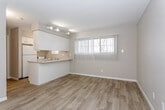 Located at 1152 County Line Rd in Kansas City, Kansas, this single-floor unit offers a practical and well-organized layout designed for comfortable everyday living. The main living area features light wood-look flooring that extends throughout, neutral-toned textured walls, and a panel entry door that welcomes natural light. Large windows fitted with vertical blinds allow ample daylight to fill the space while offering privacy.

The kitchen is positioned in an open-concept arrangement, separated from the living area by a peninsula counter that provides both workspace and a casual dining surface. White cabinetry offers generous storage overhead, while a white refrigerator and built-in stovetop round out the functional appliances. Track lighting mounted above the kitchen area ensures the cooking space is well illuminated.

The bedroom is a quiet, carpeted retreat with its own large window dressed in vertical blinds, offering a soft and comfortable atmosphere. Its direct connection to the rest of the unit makes for a seamless flow throughout the home.

The bathroom is efficiently designed, featuring wood-look flooring, a single-basin vanity with a light countertop, white cabinetry below, and a tiled shower-tub combination. Textured walls add subtle character to the space. Overall, the unit presents a clean, neutral palette that provides a versatile canvas for personalization.