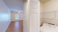 This single-story, two-bedroom, one-bathroom residence in New Orleans, Louisiana offers a practical and well-organized layout. The open-concept living area is finished with warm wood-style laminate flooring and features a ceiling fan with light fixture, creating a comfortable and airy atmosphere. Natural light enters through blinded windows, lending brightness to the neutral-toned interior throughout.

The kitchen is a functional centerpiece of the home, outfitted with warm wood cabinetry, dark countertops, a tile backsplash, and a full suite of appliances including a refrigerator, range, microwave, and dishwasher. A center island provides additional workspace and casual dining potential, while the open sightlines connect the kitchen to the main living space seamlessly.

Both bedrooms are carpeted for comfort, each equipped with a ceiling fan and window with blinds. The rooms offer clean, neutral walls and ample space for furnishings. The full bathroom includes tile flooring, a wood-toned vanity, and a shower/tub combination.

A dedicated in-unit laundry closet houses a full-size washer and dryer with wire shelving above for additional storage, adding notable convenience to daily living.