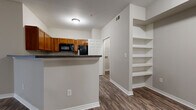 This single-floor residence offers a functional and comfortable layout designed for everyday living. The kitchen is well-equipped with warm honey-toned cabinetry, dark granite-style countertops, a full suite of black appliances including a range, microwave, and refrigerator, and a peninsula that opens to the adjacent living and dining area. Built-in open shelving near the kitchen provides convenient storage and display space.

The living area features durable wood-look flooring, a ceiling fan, and a sliding glass door fitted with vertical blinds, allowing for natural light and easy outdoor access. The open flow between the kitchen and living spaces creates a cohesive, airy feel throughout the main area.

The bedrooms are carpeted for comfort and each includes mirrored sliding-door closets for ample storage. One bedroom benefits from access to a spacious walk-in closet with wire shelving. A dedicated laundry room is equipped with washer/dryer hookups, overhead wire shelving, and matching wood-look flooring.

The bathroom features a full tiled tub-shower combination, wood-look flooring, cabinetry for storage, and clean, neutral finishes. Neutral wall tones and consistent flooring throughout the unit create a cohesive and move-in-ready aesthetic.