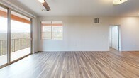 Located at 141 36th St in Los Alamos, New Mexico, this well-appointed single-story home offers three bedrooms and two full bathrooms within a thoughtfully designed floor plan. The open-concept kitchen and living area serves as the heart of the home, featuring wood-look vinyl plank flooring, a large granite-topped peninsula with pendant lighting, warm wood cabinetry, stainless steel appliances including a gas range, microwave, and refrigerator, and a built-in fireplace that anchors the living space. A sliding glass door and windows invite natural light throughout.

The bedrooms are carpeted for comfort, each equipped with a ceiling fan. The primary bedroom is a generously sized private retreat. Both bathrooms carry consistent design elements, including wood-grain cabinetry, granite countertops, and wood-look flooring. The primary bathroom features a glass-enclosed shower, while the second bathroom offers a full tub-shower combination with grab bars. A dedicated laundry room with full-size washer and dryer hookups adds everyday convenience. The home's clean, neutral palette and modern finishes create a cohesive and comfortable living environment throughout.