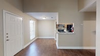This single-story, one-bedroom, one-bathroom unit offers a well-considered layout with a blend of comfort and functionality. The living room serves as the focal point of the space, featuring a classic brick fireplace with a dark mantel, vaulted ceilings, and a ceiling fan with integrated lighting. Carpet covers the living area, while hardwood-style flooring extends through the entry and into the kitchen and dining areas. Natural light enters through blinds-fitted windows, and a sliding glass door provides access to an outdoor area.

The kitchen is efficiently designed in a galley configuration, equipped with dark cabinetry, granite-style countertops, black appliances including a coil-burner range and refrigerator, and a stainless steel sink. A half-wall pass-through connects the kitchen to the adjacent dining and living areas, enhancing the open feel. A textured ceiling is present throughout much of the unit.

The bedroom includes plush carpeting and a spacious reach-in closet with double doors and a full-width hanging rod. The bathroom features hardwood-style flooring, a soaking tub with tiled surround incorporating a decorative accent border, and a dark-stained door for a polished finish.