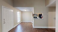 This single-story, one-bedroom, one-bathroom unit offers a well-considered layout with a blend of comfort and functionality. The living room serves as the focal point of the space, featuring a classic brick fireplace with a dark mantel, vaulted ceilings, and a ceiling fan with integrated lighting. Carpet covers the living area, while hardwood-style flooring extends through the entry and into the kitchen and dining areas. Natural light enters through blinds-fitted windows, and a sliding glass door provides access to an outdoor area.

The kitchen is efficiently designed in a galley configuration, equipped with dark cabinetry, granite-style countertops, black appliances including a coil-burner range and refrigerator, and a stainless steel sink. A half-wall pass-through connects the kitchen to the adjacent dining and living areas, enhancing the open feel. A textured ceiling is present throughout much of the unit.

The bedroom includes plush carpeting and a spacious reach-in closet with double doors and a full-width hanging rod. The bathroom features hardwood-style flooring, a soaking tub with tiled surround incorporating a decorative accent border, and a dark-stained door for a polished finish.