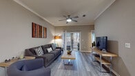 Located at 9005 Post Canyon Ln in Charlotte, NC, this single-floor residence offers a thoughtfully designed layout with modern finishes throughout. The living area features wood-look flooring, crown molding, a ceiling fan, and sliding glass doors that open to a private balcony overlooking lush, wooded surroundings, filling the space with natural light.

The kitchen is well-equipped with rich, dark espresso cabinetry, granite countertops, a tile backsplash, stainless steel appliances including a range, microwave, refrigerator, and dishwasher, plus a deep undermount sink with a gooseneck faucet and pendant lighting above the counter.

The primary bedroom offers plush carpeting and a ceiling fan, while the secondary bedroom features an eye-catching accent wall, dual windows for abundant natural light, and its own ceiling fan. Both rooms include closet storage.

Two bathrooms maintain the home's cohesive aesthetic with granite-topped dark vanities and wood-look flooring. One bathroom includes a shower-tub combo, while the larger primary bath offers both a separate glass-enclosed shower and a soaking tub, providing a spa-like experience. The overall ambiance is modern, comfortable, and well-lit throughout.