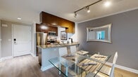 Located on Ventura Boulevard in the Encino neighborhood of Los Angeles, this 2-bedroom, 3-bathroom residence offers a thoughtfully designed single-floor layout that maximizes comfort and functionality. The open-concept kitchen and living area serves as the heart of the home, where rich dark wood cabinetry, granite countertops, and stainless steel appliances define a sleek, modern kitchen. A breakfast bar with seating provides a casual dining option alongside a dedicated dining area with a glass-top table. The living room is bright and inviting, featuring light hardwood flooring, crown molding, and sliding glass doors that open directly to a private outdoor patio, allowing natural light to fill the space. The primary bedroom is generously sized, highlighted by a teal accent wall, light hardwood floors, floor-to-ceiling mirrored closet doors, and a large window with outdoor views. A private en-suite bathroom completes the suite. The second bedroom also features a calming teal accent wall and access to natural light. All three bathrooms are finished with granite-topped dark wood vanities and tiled flooring. A dedicated closet adds additional storage. The overall ambiance is contemporary and cohesive throughout.