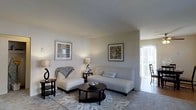 Located at 760 Eayerstown Road in Lumberton, New Jersey, this single-floor residence combines comfort and functionality in a clean, well-maintained layout. The living area serves as the heart of the home, featuring smooth neutral-toned walls that create a calm and inviting atmosphere. Soft, diffused lighting complements the space, while a sliding glass door allows natural light to filter in and provides a seamless connection to the outdoors. The room is thoughtfully proportioned, offering ample space for comfortable seating arrangements centered around a classic round coffee table. Subtle architectural details, including gently angled ceilings, add visual interest without overwhelming the understated elegance of the interior. The neutral color palette throughout lends itself to versatile decorating possibilities and enhances the overall sense of openness. Wall art and carefully placed accent lighting contribute to a warm, residential ambiance. The single-level design ensures easy accessibility and a cohesive flow from room to room, making the space both practical and inviting for everyday living.