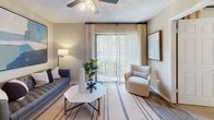 This efficiently designed one-bedroom, one-bathroom unit offers a well-organized layout across a single floor, making practical use of every square foot. The living room serves as the central gathering space, featuring wood-style flooring, a ceiling fan with light fixture, and a large sliding glass door dressed with vertical blinds and drape panels that fill the room with natural light and provide access to an outdoor area. The entry door opens directly into this space, creating a welcoming and open feel.

The kitchen is positioned adjacent to the living area and is outfitted with white shaker-style cabinetry, a white subway tile backsplash, granite-tone countertops, and black appliances including a refrigerator, range, microwave, and dishwasher. A skylight above the kitchen adds additional brightness. A dedicated laundry closet with a stacked washer and dryer unit is conveniently located just off the kitchen.

The bedroom offers plush carpeting, a ceiling fan, and its own sliding glass door with outdoor views of greenery and a balcony. A closet provides storage within the room. The bathroom includes a single-sink vanity with a granite-tone countertop and a separate tub-shower combination, finished with wood-style flooring.
