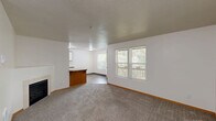 Located at 7680 SW 74th Ave in Portland, Oregon, this single-floor, 3-bedroom, 2-bathroom home offers a practical and comfortable layout. The living room serves as a welcoming central space, featuring plush carpeting, a tiled fireplace, and a textured ceiling, with direct access to the entryway and adjoining rooms. The kitchen is efficiently designed with oak-trimmed white cabinetry, granite-style laminate countertops, wood-style vinyl flooring, and white appliances including a coil-top range and refrigerator. A dining area adjacent to the kitchen benefits from natural light through a window and provides access to an outdoor deck, offering views of surrounding greenery. The three bedrooms are carpeted throughout, each with neutral walls, wood trim, and natural light from windows with blinds. Two of the bedrooms are equipped with sliding closet doors for practical storage. The primary bedroom includes a closet and connects conveniently to the layout. Both bathrooms feature tub-shower combinations with chrome fixtures and clean white surrounds, with one including wood-style flooring. The home maintains a consistent, clean aesthetic with warm wood accents and textured ceilings throughout.