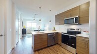 This well-appointed single-floor residence showcases a thoughtfully designed open-concept layout with contemporary finishes throughout. The kitchen serves as the heart of the home, featuring warm wood-toned cabinetry, crisp white quartz countertops, and a full suite of stainless steel appliances including a range, microwave, dishwasher, and refrigerator. A peninsula with bar seating and stylish pendant lighting overhead creates a natural gathering space and seamlessly connects the kitchen to the living area. Wood-look flooring flows continuously throughout the unit, adding warmth and cohesion to the space.

The living area is bright and inviting, benefiting from a large window that allows ample natural light and provides views of the surrounding neighborhood. A ceiling fan adds both function and style to the room.

Two comfortable bedrooms each feature large windows with expansive outdoor views, allowing natural light to fill the spaces. The bathroom is finished with striking marble-look tile in the tub and shower surround, complemented by wood-toned cabinetry for storage.

Overall, the residence strikes a balance between modern design and functional living, with clean lines, neutral tones, and quality finishes creating a bright, cohesive, and welcoming atmosphere throughout.