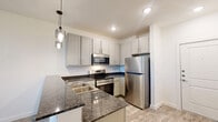 Located at 100 E Vaughn St in Cleburne, TX, this efficiently designed one-bedroom, one-bathroom unit offers a thoughtful single-story layout that maximizes every square foot. The open-concept living and dining area flows seamlessly from the kitchen, creating a bright, connected space filled with natural light from well-placed windows. A ceiling fan keeps the living area comfortable year-round, while a front entry door adds to the welcoming feel.

The kitchen is a standout feature, boasting grey shaker-style cabinetry, dark granite countertops, and a full suite of stainless steel appliances including a refrigerator, range, over-the-range microwave, and dishwasher. A peninsula with a double-basin sink and stylish pendant lighting above adds both function and visual appeal. Wood-look luxury vinyl plank flooring runs throughout the entire unit, tying the spaces together with a clean, modern aesthetic.

The bedroom is a comfortable retreat with a ceiling fan, a window with outdoor views, and ample closet storage provided by two closets. The bathroom features a granite-topped vanity, matching cabinetry, and a full tub-shower combination. A private patio rounds out the unit, offering an outdoor space for relaxation.