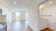 Located at 4225 SE Milwaukie Ave in Portland's vibrant SE neighborhood, this efficiently designed unit offers a clean, modern aesthetic throughout its single floor. The open-concept kitchen and living area is anchored by a sleek, contemporary kitchen featuring flat-front white cabinetry extending to the ceiling, white quartz countertops, a subway tile backsplash, and a full suite of stainless steel appliances including a refrigerator, electric range, over-the-range microwave, and dishwasher. Light wood-tone flooring runs continuously throughout the space, contributing to a warm, cohesive feel. The living area benefits from a tall, floor-to-ceiling window that floods the room with natural light and offers views of surrounding treetops and the Portland cityscape. An in-unit washer is tucked behind louvered closet doors, adding everyday convenience. A transom window above the entry door provides additional light to the entryway. The bathroom is finished with consistent modern detailing, including a tub/shower combo, chrome fixtures, a vanity with drawer storage, and matching wood-tone flooring. The overall design is bright, minimal, and functional — ideal for those seeking a well-appointed space in Southeast Portland.