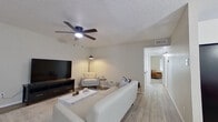 This single-floor residence is designed with a clean, contemporary aesthetic that balances comfort and functionality across its thoughtfully arranged layout. The living area features light wood-look flooring, a textured ceiling, and a ceiling fan with integrated lighting, creating a bright and comfortable atmosphere. Large windows fitted with white blinds allow natural light to fill the space, complementing the neutral wall tones and modern furnishings.

Adjacent to the living room, the dining area is distinguished by a striking geometric chandelier, a round dining table, and a wall-mounted mirror that amplifies the sense of space. The kitchen is outfitted with white shaker-style cabinetry, matte black hardware, quartz-look countertops, a marble-style subway tile backsplash, and a black electric range with an overhead ventilation hood.

The bedrooms feature plush carpeting, ceiling fans, and ample closet space with dual doors. Natural light enters through well-sized windows, enhancing the comfortable and restful character of each room. The bathroom is finished with white subway tile walls, a quartz-topped vanity, matte black fixtures, and a gold-framed round mirror, delivering a polished and modern feel throughout.
