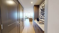 Located on Pacific Ave in the heart of Dallas, TX, this well-appointed one-bedroom, one-bathroom residence offers a thoughtfully designed layout across a single floor. The open-plan living room immediately impresses with expansive floor-to-ceiling windows framing breathtaking panoramic views of the Dallas skyline, including the iconic Fountain Place tower. Light wood flooring and crisp white walls create a bright, contemporary ambiance throughout.

The kitchen is a standout feature, boasting rich wood cabinetry, sleek quartz countertops with striking veining, a large center island, and stainless steel appliances — all illuminated by recessed lighting above light hardwood floors.

The spacious primary bedroom continues the floor-to-ceiling window theme, offering more sweeping city views and plush carpeting. It connects directly to a well-organized walk-in closet with multi-tiered shelving and hanging rails, as well as a private bathroom finished in large-format beige tiles, featuring a frameless glass-enclosed walk-in shower with marble-style tile surround and a built-in bench. A ceiling fan, wall-mounted TV provision, and access to the en-suite bathroom complete the bedroom. The residence also includes a dedicated hallway connecting all rooms efficiently.