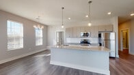 Located at 2875 Olentangy River Rd in Columbus, Ohio, this contemporary single-floor residence showcases a thoughtfully designed open-concept layout. The kitchen serves as the centerpiece of the living area, featuring a large island with granite countertops, an undermount sink, and stylish pendant lighting overhead. Gray flat-front cabinetry lines the walls, complemented by a classic white subway tile backsplash and a full suite of stainless steel appliances, including a range, built-in microwave, and refrigerator. Rich, dark-toned hardwood-style flooring flows throughout the main living areas, while recessed and decorative chandelier lighting add warmth and character. Multiple windows dressed with blinds invite generous natural light into the dining and living spaces, which also feature direct access to an exterior door. The bedrooms are carpeted and bright, each benefiting from natural light through well-positioned windows. A spacious walk-in closet with wire shelving provides ample storage. The bathroom is elegantly appointed with a granite-topped vanity with gray cabinetry, a tub-shower combination with marble-style tile surround, and brushed nickel fixtures throughout. The overall aesthetic is clean, modern, and move-in ready.