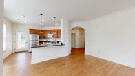 Located at 357 Windigrove Dr in Waynesboro, VA, this single-story, 2-bedroom, 2-bathroom home offers a thoughtfully designed layout with comfortable living spaces throughout. The open-concept living and dining area greets you at the entrance, featuring warm hardwood-style flooring, crown molding, a ceiling fan, and multiple windows that fill the space with natural light. An elegant arched doorway connects the living area to the rest of the home, adding an architectural detail that enhances the overall flow. The kitchen is well-appointed with rich wood cabinetry, dark granite countertops, stainless steel appliances including a refrigerator, range, and microwave, and pendant lighting over a breakfast bar — ideal for both everyday cooking and entertaining. Both bedrooms are carpeted and offer a quiet, comfortable retreat, with ample closet space including a generously sized walk-in closet with built-in wire shelving. The bathrooms feature hardwood-style flooring, wood vanities with granite countertops, and a shower-tub combination. A dedicated in-unit laundry room adds everyday convenience, and a utility room provides additional storage. The home's clean, neutral palette and consistent finishes create a cohesive and inviting atmosphere throughout.