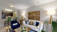 Located in Raleigh, NC, this single-story 2-bedroom, 2-bathroom home offers a thoughtfully designed layout with a seamless flow between living, dining, and kitchen areas. The living room is a welcoming centerpiece, featuring crown molding, neutral walls, plush carpeting, and natural light streaming through large windows dressed with floor-length drapes. The kitchen is equipped with rich dark cabinetry, granite-style countertops, tile flooring, and black appliances including a refrigerator, range, microwave, and dishwasher, with an open pass-through view to the living area. The dining room sits conveniently adjacent, completing the entertaining space. The primary bedroom is generously sized, offering carpet flooring, natural light from a large window, and ample closet space. The second bedroom mirrors this comfort with similar finishes and a bright window. Both bathrooms feature dark wood vanities with granite countertops and tub-shower combinations with tile surrounds. A dedicated laundry area, utility room, and three closets add to the home's functionality. A hallway connects the private spaces with ease, and the overall layout is efficient and comfortable throughout.