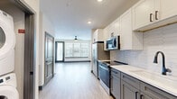 Located at 944 Broadcast Pl in Jacksonville, FL, this well-designed one-bedroom, one-bathroom residence offers a thoughtful layout across a single floor. The open-concept kitchen and living area serves as the heart of the home, featuring light wood-look flooring, recessed lighting, and a ceiling fan. The kitchen is outfitted with stainless steel appliances — including a refrigerator, range, and built-in microwave — complemented by two-tone cabinetry in white and gray, white quartz countertops, and a hexagonal tile backsplash. Large windows and a glass door flood the living area with natural light and provide outdoor views. The spacious bedroom features plush carpet, a ceiling fan, and ample natural light from a wide window. The well-appointed bathroom includes a dual-sink vanity with gray cabinetry, black hardware, a wall-mounted light fixture, and a glass-enclosed walk-in shower with white tile. A generously sized walk-in closet with built-in shelving and hanging systems provides excellent storage. Additional highlights include a dedicated office space, three closets total, and a convenient in-unit laundry area with a stacked washer and dryer.
