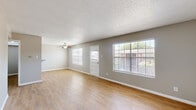 This single-story, 2-bedroom, 1-bathroom home offers a functional and well-appointed layout across its single floor. The spacious living room serves as the heart of the home, featuring warm wood-look flooring, a textured ceiling, a ceiling fan with light fixture, and multiple large windows fitted with blinds that invite an abundance of natural light. A dedicated entrance leads directly into this open area, which connects seamlessly to the kitchen via a pass-through counter opening.

The galley-style kitchen is efficiently designed with white cabinetry, light stone-look countertops, a tile backsplash, and stainless steel appliances including a gas range, refrigerator, and dishwasher. Track lighting overhead ensures the space is well-lit for cooking and meal preparation.

Both bedrooms continue the wood-look flooring and neutral gray wall palette, with ceiling fans and windows providing ventilation and natural light. The spacious primary bedroom offers comfortable proportions. Two closets are present in the home, including one walk-in style closet equipped with built-in shelving and a hanging rod for organized storage.

The single bathroom features a white vanity with a light countertop, a mirror, and a shower-tub combination. A hallway connects the private areas of the home, completing this practical and move-in-ready layout.