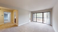 This single-floor residence offers a well-organized layout that balances open living spaces with private quarters. The main living area is generously sized, featuring neutral-toned carpet, crisp white walls, and a large sliding glass door that opens directly onto a private balcony. The outdoor views of surrounding trees provide a natural backdrop, and the additional side window ensures the room remains bright throughout the day.

The kitchen is thoughtfully updated, featuring a galley-style design with cream shaker cabinetry, matte black hardware, light quartz countertops, a white subway tile backsplash, and stainless steel appliances including a gas range, refrigerator, and built-in microwave. Light wood-look flooring runs throughout the kitchen, adding warmth to the space.

Two carpeted bedrooms each offer windows framing wooded views, providing a calm and private atmosphere. Both bathrooms are finished with white vanities, light wood-look tile flooring, and matte black fixtures and towel bars. One bathroom includes a tiled shower enclosure. A ceiling fan is also present in the living area, contributing to overall comfort and functionality.