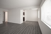 Located at 1600 Pennwood Drive in Hampton, Virginia, this single-story unit offers a clean, updated interior with a cohesive neutral palette throughout. The layout, as revealed by the floor plan, flows logically from the entry areas through the living spaces and into the kitchen.

The living and dining areas are generously sized, featuring durable gray-toned vinyl plank flooring that extends consistently throughout the unit. Large windows allow natural light to fill these spaces, creating a bright and open atmosphere. The open sightlines between the living and dining areas enhance the sense of spaciousness.

The galley-style kitchen is well-appointed with rich dark espresso cabinetry, light granite-patterned countertops, and black appliances including a gas range and built-in microwave. A stainless steel sink and ample cabinet storage complete this functional cooking space.

The bedrooms are comfortably sized, each featuring the same vinyl plank flooring, neutral walls, and windows that bring in natural light. At least one bedroom includes a bifold-door closet with a full-width hanging rod for organized storage.

The bathroom presents a classic black-and-white aesthetic, with white subway tile surrounding a full soaking tub and shower combination, accented by a bold black tile border. Light tile flooring and crisp white fixtures round out the space.