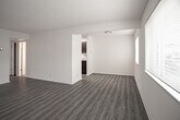 Located at 1600 Pennwood Drive in Hampton, Virginia, this single-story unit offers a clean, updated interior with a cohesive neutral palette throughout. The layout, as revealed by the floor plan, flows logically from the entry areas through the living spaces and into the kitchen.

The living and dining areas are generously sized, featuring durable gray-toned vinyl plank flooring that extends consistently throughout the unit. Large windows allow natural light to fill these spaces, creating a bright and open atmosphere. The open sightlines between the living and dining areas enhance the sense of spaciousness.

The galley-style kitchen is well-appointed with rich dark espresso cabinetry, light granite-patterned countertops, and black appliances including a gas range and built-in microwave. A stainless steel sink and ample cabinet storage complete this functional cooking space.

The bedrooms are comfortably sized, each featuring the same vinyl plank flooring, neutral walls, and windows that bring in natural light. At least one bedroom includes a bifold-door closet with a full-width hanging rod for organized storage.

The bathroom presents a classic black-and-white aesthetic, with white subway tile surrounding a full soaking tub and shower combination, accented by a bold black tile border. Light tile flooring and crisp white fixtures round out the space.