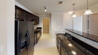 Located at 7205 Aventine Way in Chattanooga, Tennessee, this single-floor residence offers a well-organized layout designed for comfortable everyday living. The galley-style kitchen is a standout feature, appointed with rich dark cabinetry, dark granite countertops, a double basin sink, pendant lighting, and a full suite of black appliances including a refrigerator, range, and built-in microwave. Tile flooring and track lighting complete the functional yet stylish space. The open living and dining area is finished with warm neutral carpet and crown molding throughout, bathed in natural light from windows with blinds. A chandelier anchors the dining area, while a ceiling fan serves the living space, which opens toward the kitchen via a peninsula counter. Each bedroom features plush carpeting, a ceiling fan with light fixture, and windows that bring in natural light. The primary bathroom includes a vanity with extended countertop, ample cabinetry, a soaking tub with tile surround, and tile flooring. The secondary bathroom mirrors a clean, functional design with a tub-shower combo and tile floors. A dedicated laundry room houses a full-size washer and dryer with overhead shelving, adding everyday convenience to this well-appointed Chattanooga residence.