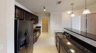 Located at 7205 Aventine Way in Chattanooga, Tennessee, this single-floor residence offers a well-organized layout designed for comfortable everyday living. The galley-style kitchen is a standout feature, appointed with rich dark cabinetry, dark granite countertops, a double basin sink, pendant lighting, and a full suite of black appliances including a refrigerator, range, and built-in microwave. Tile flooring and track lighting complete the functional yet stylish space. The open living and dining area is finished with warm neutral carpet and crown molding throughout, bathed in natural light from windows with blinds. A chandelier anchors the dining area, while a ceiling fan serves the living space, which opens toward the kitchen via a peninsula counter. Each bedroom features plush carpeting, a ceiling fan with light fixture, and windows that bring in natural light. The primary bathroom includes a vanity with extended countertop, ample cabinetry, a soaking tub with tile surround, and tile flooring. The secondary bathroom mirrors a clean, functional design with a tub-shower combo and tile floors. A dedicated laundry room houses a full-size washer and dryer with overhead shelving, adding everyday convenience to this well-appointed Chattanooga residence.
