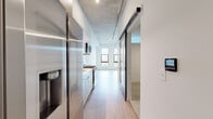 Located at 370 W 12th Ave in Denver's vibrant West Colfax neighborhood, this modern one-bedroom, one-bathroom residence offers a thoughtfully designed layout across a single floor. The unit showcases an industrial-modern aesthetic, highlighted by striking exposed concrete ceilings that contrast beautifully with crisp white walls and light wood-tone flooring throughout the main living areas.

The galley-style kitchen is efficiently designed with light wood cabinetry, a stainless steel refrigerator with water dispenser, a gas range, microwave, and a tile backsplash — all optimized for smart use of space. A central hallway connects the living areas and features black-accented sliding doors and barn-style hardware that reinforce the modern aesthetic. The spacious living room is bathed in natural light through large black-framed windows offering open city views of the Denver skyline.

The bedroom is carpeted for comfort and includes a generous closet with sleek dark sliding panel doors and a high clerestory window for added natural light. The bathroom features warm wood cabinetry, a clean white countertop, and light tile flooring. An in-unit laundry area adds everyday convenience. This residence combines urban industrial design with functional, contemporary living in the heart of Denver.