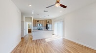 This two-story home offers a well-designed layout spread across two floors, combining functionality with modern finishes throughout. The main floor hosts the primary living areas, including an open-concept kitchen and living room that seamlessly connect to create a generous communal space. The kitchen is appointed with light wood cabinetry, granite countertops, a subway tile backsplash, stainless steel appliances, and a central island with pendant lighting — all anchored by warm-toned hardwood-style flooring. A ceiling fan enhances the living area, which benefits from natural light streaming through sliding glass doors. The main floor also includes an attached two-car garage with an automatic opener, offering ample storage and parking. Upstairs, the primary bedroom is a comfortable retreat, featuring plush carpeting, natural light from dual windows, and dedicated closet space. The second bedroom mirrors this layout with its own closet and hardwood-style flooring. Both bathrooms are finished with clean, contemporary fixtures; one features a tiled walk-in shower with a glass enclosure, a white vanity, and wood-look flooring. Two staircases and hallways connect the floors, ensuring smooth circulation throughout the home.
