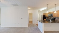 This single-floor residence offers four bedrooms, one bathroom, and a thoughtfully arranged layout that maximizes functionality. The open-concept kitchen and living area serves as the heart of the home, where a peninsula with dark granite countertops and a built-in sink creates a natural divide between the two spaces. The kitchen is outfitted with warm honey-toned cabinetry, a tile backsplash in a diamond pattern, stainless steel refrigerator, microwave, and range. Pendant lights hang above the peninsula, complemented by track lighting overhead, while the adjoining living area features durable hardwood-style flooring transitioning to plush carpeting.

The four bedrooms are carpeted and each equipped with a ceiling fan, offering comfort and practicality. The primary bedroom is generously sized and includes a walk-in closet with wire shelving for organized storage. Natural light filters in through windows fitted with horizontal blinds. The full bathroom features tile flooring, a tub-shower combination with white tile surround, a toilet, and a wood-toned vanity with a white sink and mirror. A dedicated utility room rounds out the functional layout of this well-appointed residence.