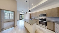Located at 1050 Blanch St in West Palm Beach, FL, this thoughtfully designed one-bedroom, one-bathroom unit offers a modern living experience within a compact, efficient floor plan. The open-concept kitchen and dining area serves as the heart of the home, showcasing light wood cabinetry, subway tile backsplash, dark quartz countertops, and a full suite of stainless steel appliances including a range, microwave, dishwasher, and French door refrigerator. A central island with pendant lighting adds both function and style, while soaring ceilings amplify the sense of space throughout. Light-toned luxury flooring runs through the main living areas, enhancing the bright and airy ambiance. The living room opens via glass doors to a private patio enclosed by modern metal railings, offering views of lush tropical landscaping. The bedroom features soft carpeting, a large window with natural light, and access to generous closet space with built-in wire shelving systems. The bathroom is finished with large-format marble-style tile in the tub/shower surround, a wood-toned vanity with quartz countertop, and an illuminated frameless mirror. An in-unit laundry area adds everyday convenience to this well-appointed West Palm Beach residence.