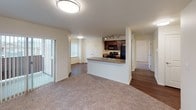 Located at 2865 W. Elliott Drive in Spokane, Washington, Unit A302 is a single-floor residence that combines practical design with comfortable living. The kitchen is a standout feature, showcasing rich dark-wood cabinetry, warm countertops, and a full suite of black appliances including a gas range, built-in microwave, and refrigerator. Track lighting illuminates the space, while a double stainless steel sink and ample counter space make it highly functional. A peninsula-style counter opens the kitchen toward the living area, creating a connected, open feel. The living room is generously sized with neutral carpet flooring and access to natural light through vertical-blind-covered windows. The layout flows naturally into the bedroom areas, one of which features a ceiling fan with light fixture and a baseboard heater, while another offers a window-mounted air conditioning unit. Both bedrooms are finished with plush carpeting. The bathroom is well-designed with dark wood vanity cabinetry, a large mirror, a combination tub and shower, and hardwood-style flooring. Throughout the unit, hardwood-style flooring in the kitchen and hallways transitions seamlessly to carpet in the living and sleeping areas, lending warmth and cohesion to the overall aesthetic. A double-door closet adds convenient storage near the kitchen.