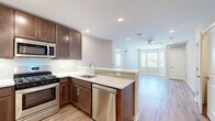This well-appointed two-bedroom, two-bathroom residence at 8 Kingsbridge Road, Unit 309 in Fairfield, NJ offers a thoughtfully designed single-floor layout with modern finishes throughout. The open-concept kitchen and living area serves as the heart of the home, featuring rich dark-brown shaker cabinetry, light quartz countertops, a classic subway tile backsplash, and a full suite of stainless steel appliances including a gas range, built-in microwave, dishwasher, and French door refrigerator. A peninsula counter seamlessly connects the kitchen to the living area, which is finished with warm wood-look flooring, recessed lighting, and a ceiling fan. A striking bay window floods the living space with natural light and offers open views of the surrounding area. The primary bedroom provides a generous retreat with plush carpeting, a ceiling fan, a walk-in closet, and an en-suite bathroom featuring a glass-enclosed shower. The second bedroom is equally comfortable, also carpeted with its own ceiling fan. A second full bathroom includes a tub-shower combination with clean white tile surround and a wood-tone vanity with quartz countertop. A dedicated hallway and closet complete the practical layout of this move-in ready residence.