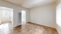 Located at 15001 Crenshaw Blvd in Gardena, California, this single-floor unit offers a well-organized layout comprising a living room, kitchen, bathroom, hallway, and three closets. Consistent warm-toned ceramic tile flooring runs throughout the space, providing a cohesive and easy-to-maintain surface.

The living room is bright and open, featuring a large window with vertical blinds that allows natural light to fill the room. A wall-mounted heater unit provides climate control, and a textured ceiling adds a subtle design detail. The entry door opens directly into this main living area.

The galley-style kitchen is efficiently designed with white cabinetry above and below the counter, a stainless steel sink with a light-colored countertop, and a white gas range. A window above the counter area brings in additional natural light, keeping the space feeling airy despite its compact footprint.

The bathroom features a clean, all-white tiled tub and shower combination equipped with chrome fixtures, a showerhead, and a tub spout. A window positioned above the tub provides ventilation and natural light.

Three closets distributed throughout the unit offer practical storage solutions. The hallway connects the various rooms, contributing to a functional and straightforward floor plan. Overall, the space presents a clean, neutral palette suited for efficient everyday living.
