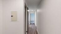 Located in Seattle's Queen Anne neighborhood at Garfield Street, this two-bedroom, one-bathroom residence offers a thoughtfully designed layout across a single floor. The open-concept living room and kitchen area is anchored by light-toned hardwood-style flooring that runs throughout, with large windows and a sliding glass door flooding the space with natural light. The private balcony accessed from the living area offers views toward the waterfront and surrounding cityscape, a standout feature of this residence.

The kitchen is well-appointed with stainless steel appliances—including a refrigerator, range, and over-the-range microwave—complemented by two-toned cabinetry featuring white upper cabinets and dark wood lower cabinets, a tile backsplash, and light countertops.

A clean hallway with wood-style flooring and recessed lighting connects the main living areas to the private rooms. Both bedrooms are carpeted and receive natural light through windows with urban views. The primary bedroom includes a double sliding-door closet with built-in shelving and hanging rod. The bathroom features tile wall accents, a pedestal sink, mirrored medicine cabinet, and wood-style flooring, maintaining the clean, modern aesthetic found throughout the residence.