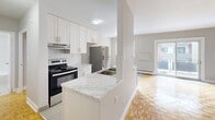 Located at 296 Grenfell St in Oshawa, Ontario, this one-bedroom, one-bathroom unit offers a functional and well-appointed single-floor layout. The space is characterized by warm parquet wood flooring throughout the living areas and bedroom, lending a classic and inviting feel to the interior.

The kitchen is a standout feature, equipped with crisp white cabinetry, a white subway tile backsplash, stainless steel appliances including a refrigerator and electric range, and a peninsula counter finished with marble-look countertops. Light tile flooring in the kitchen provides a clean contrast to the parquet in the adjacent living area, creating a natural visual separation between spaces.

The bedroom is a comfortable, well-proportioned room with a window that allows in natural light and offers views of the surrounding neighbourhood. Baseboard heating units are present throughout, ensuring efficient climate control.

The bathroom features a full bathtub and shower combination, finished with white subway tile surround and chrome fixtures, presenting a clean and timeless aesthetic.

Overall, the unit maintains a neutral colour palette of whites and soft greys, contributing to a bright and airy ambiance throughout. The thoughtful layout makes efficient use of the available space, offering practical living in a well-connected Oshawa location.