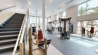 Located at 20600 North 55th Street in Phoenix, AZ, this expansive two-story fitness facility offers a comprehensive workout environment spread across two generously sized floors of nearly equal area. The modern architectural design is defined by soaring double-height ceilings on the main level, large floor-to-ceiling glass walls, and an open, airy layout that floods the space with abundant natural light and sweeping views of the surrounding desert landscape and palm trees.

The ground floor houses a well-equipped exercise room featuring strength training machines, free weights, adjustable benches, a Smith machine, cable systems, and cardio equipment including treadmills and ellipticals. A striking geometric wood-paneled accent wall near the entrance adds a bold design element, complemented by a reception area with digital displays. Durable rubber and speckled flooring throughout ensures functionality and safety.

A glass-railed staircase leads to the upper floor, which features a second exercise room with an open carpeted studio space ideal for group fitness or cycling classes, along with additional strength and cardio equipment. A mezzanine overlook connects both levels visually, enhancing the sense of scale. The entire facility benefits from panoramic outdoor views, recessed and linear lighting, and a clean, modern aesthetic throughout.