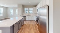 Located at 1100 Hampton Rivers Rd in Charleston, SC, this single-floor home offers a well-designed layout with contemporary finishes throughout. The living area is bright and welcoming, featuring warm hardwood-style flooring, neutral gray walls, and multiple windows that allow generous natural light to fill the space. A ceiling fan adds both function and comfort to the room.

The kitchen is a standout feature, outfitted with white shaker-style cabinetry reaching toward the ceiling, a contrasting gray island with quartz countertops, white subway tile backsplash, and a full suite of stainless steel Whirlpool appliances including a refrigerator, range, microwave, and dishwasher. A double basin sink and additional windows overlooking the exterior complete the space.

The bedrooms are carpeted for comfort and include ceiling fans and windows that bring in natural light. A well-proportioned hallway connects the private areas of the home, with closet access conveniently nearby.

The bathrooms are clean and modern, featuring white cabinetry, quartz countertops, and a tub-shower combination with a sliding glass door. A dual-sink vanity with a large mirror and brushed nickel fixtures adds a refined touch. Throughout, the home presents a cohesive, move-in-ready aesthetic ideal for comfortable living in Charleston.