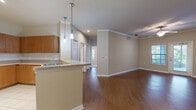 Located at 1930 Devonwood Dr. in Wesley Chapel, FL, this single-story, 3-bedroom, 2-bathroom home offers a well-designed layout with a comfortable blend of style and functionality. The living room is a standout space, featuring rich hardwood-style flooring, crown molding, a ceiling fan with light fixture, and a glass door that fills the room with natural light and provides outdoor access. An adjacent area with matching flooring and decorative chair rail molding adds to the home's classic charm.

The kitchen is efficiently designed with warm wood cabinetry extending to the ceiling, light stone-tone countertops, tile flooring, and a full suite of black appliances including a range, over-the-range microwave, and refrigerator. Louvered bifold doors provide convenient pantry or utility storage.

The bedrooms feature plush carpeting, ceiling fans, and windows with natural light. The spacious primary bedroom includes a dedicated walk-in closet outfitted with wire shelving. Both bathrooms are finished with tile flooring and warm wood vanities topped with light countertops, with one bathroom featuring a large mirror, natural light from a window, and a shower/tub combo.