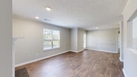 This single-story, one-bedroom, one-bathroom unit offers a practical and comfortable layout across a compact yet efficiently designed floor plan. The combined kitchen and living area serves as the heart of the home, where a galley-style kitchen impresses with crisp white shaker cabinetry, granite countertops, stainless steel appliances including a refrigerator, range, microwave, and dishwasher, and a deep undermount sink with a modern faucet. A pass-through window connects the kitchen to the living area, enhancing the open feel of the space. The living room features warm wood-look laminate flooring, neutral gray walls, a classic fireplace with a white mantel and dark surround, and windows fitted with blinds that allow natural light to filter in. A textured ceiling and crown molding add architectural character throughout the main living areas. The bedroom offers plush carpeting, a window with outdoor views, and its own closet. The bathroom is equipped with a full tub and shower combination, wood-look flooring, and brushed nickel fixtures. Recessed lighting and consistent neutral tones throughout lend the space a clean, modern, and move-in-ready character.
