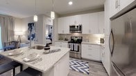 This single-floor 2-bedroom, 2-bathroom residence combines modern design with functional living. The kitchen serves as a central highlight, featuring crisp white shaker cabinetry extending to the ceiling, granite countertops, stainless steel appliances, a large kitchen island with an undermount sink, pendant lighting, and wood-style flooring. A convenient in-unit washer and dryer are tucked neatly within the kitchen area. Both bedrooms are generously sized, fitted with plush carpeting and ceiling fans. The primary bedroom offers large windows that invite natural light and outdoor views, complemented by a walk-in closet. The second bedroom also includes walk-in closet access and ample natural light. Each bathroom is finished with granite vanity countertops, white cabinetry, and modern fixtures. The primary bathroom features an extended vanity with a wide mirror, while the secondary bathroom includes a glass-enclosed shower. Neutral tones and warm lighting flow consistently throughout the residence, creating a cohesive and inviting ambiance. The thoughtful layout and quality finishes make this a comfortable and stylish living space.