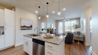 Located at 4101 Glenloch Creek in Matthews, NC, this single-floor residence offers a thoughtfully designed open-concept layout with modern finishes and abundant natural light throughout. The kitchen serves as the heart of the home, anchored by a central island with granite countertops, an undermount sink, and pendant lighting overhead. White shaker cabinetry, a subway tile backsplash, stainless steel appliances — including a refrigerator, range, microwave, and dishwasher — and durable wood-look flooring complete the space. The kitchen flows seamlessly into the living area, which features large windows with views to a private balcony, a ceiling fan, and a warm, inviting atmosphere. Two well-sized bedrooms offer plush carpeting and ample natural light; one features a textured accent wall, while both provide a tranquil retreat. The primary bathroom is finished with a double-sink granite vanity, white cabinetry, wood-look flooring, and a tiled walk-in shower, with direct access to a spacious walk-in closet with built-in shelving. A secondary bathroom offers similar quality finishes. Throughout the residence, neutral tones, recessed lighting, and clean architectural lines create a cohesive and comfortable living environment.