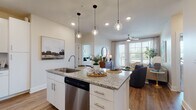 Located at 4101 Glenloch Creek in Matthews, NC, this single-floor residence offers a thoughtfully designed open-concept layout with modern finishes and abundant natural light throughout. The kitchen serves as the heart of the home, anchored by a central island with granite countertops, an undermount sink, and pendant lighting overhead. White shaker cabinetry, a subway tile backsplash, stainless steel appliances — including a refrigerator, range, microwave, and dishwasher — and durable wood-look flooring complete the space. The kitchen flows seamlessly into the living area, which features large windows with views to a private balcony, a ceiling fan, and a warm, inviting atmosphere. Two well-sized bedrooms offer plush carpeting and ample natural light; one features a textured accent wall, while both provide a tranquil retreat. The primary bathroom is finished with a double-sink granite vanity, white cabinetry, wood-look flooring, and a tiled walk-in shower, with direct access to a spacious walk-in closet with built-in shelving. A secondary bathroom offers similar quality finishes. Throughout the residence, neutral tones, recessed lighting, and clean architectural lines create a cohesive and comfortable living environment.