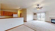 This single-floor unit offers a well-organized layout across two bedrooms and two bathrooms. The open-concept living and kitchen area forms the heart of the space, where vaulted ceilings add a sense of volume and airiness. The living room is carpeted and features a tile-surround fireplace, a ceiling fan, a wall-mounted air conditioning unit, and a sliding glass door that opens to a private balcony, allowing natural light to fill the room.

The kitchen is separated from the living area by a half-wall breakfast bar and is equipped with warm oak cabinetry, laminate countertops, tile flooring, and white appliances including a refrigerator and electric range. Track lighting overhead provides functional illumination.

Both bedrooms are carpeted and finished with neutral tones and oak wood trim. The primary bedroom is generously sized and includes a walk-in closet outfitted with shelving and hanging rods. The second bedroom features a window with outdoor views.

The two bathrooms are finished with tile flooring and oak vanity cabinetry. One includes a walk-in shower, while the other offers a full tub-shower combination. Baseboard heating is present throughout the unit.